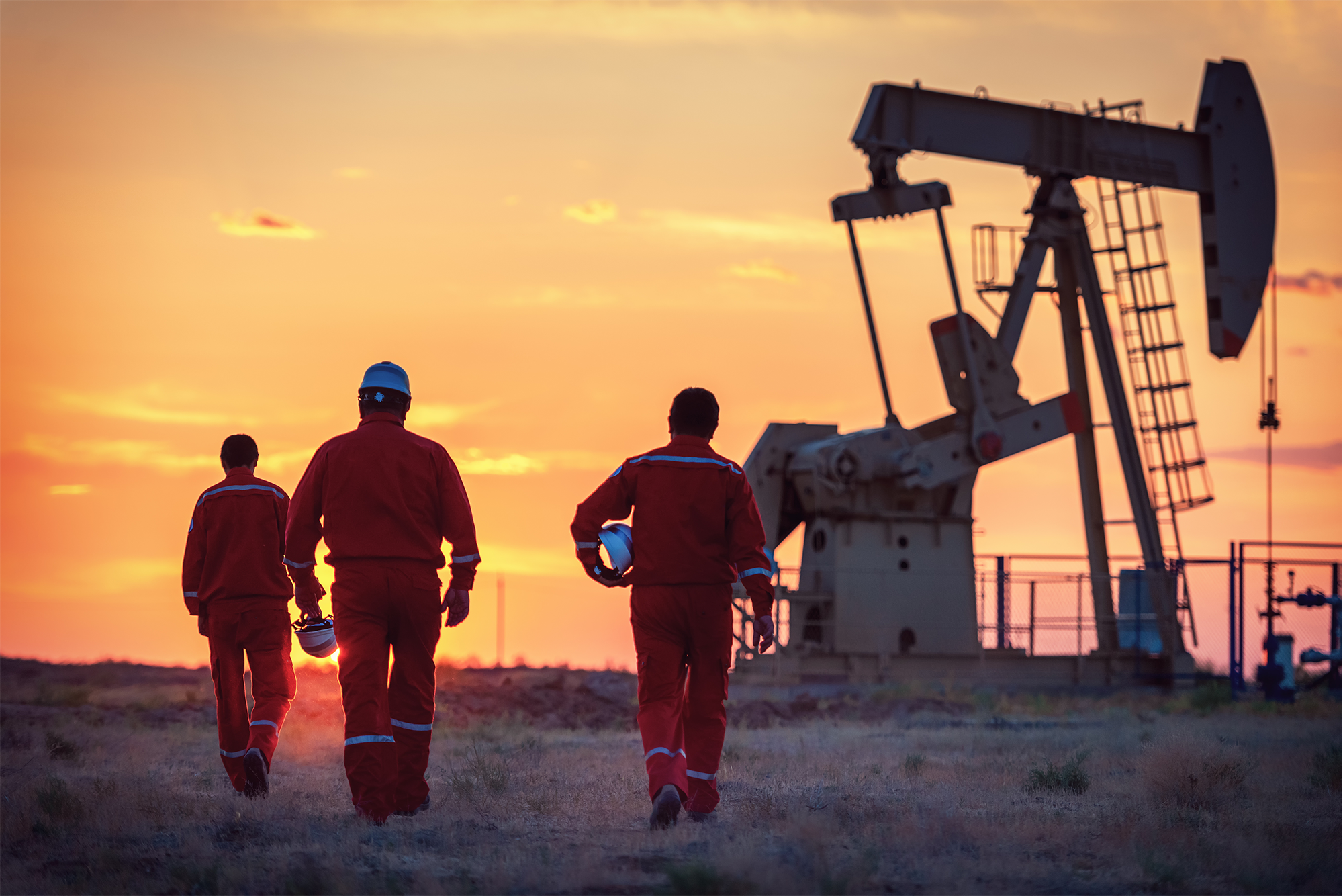 Oil and Gas Industry Coverage Options: A group of three oilfield workers walking towards an oil rig.