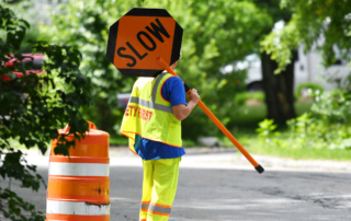 National Work Zone Awareness Week Takes Place April 15-19: A construction worker holding a slow sign in a construction work zone.