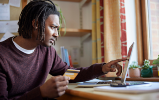 The Game-Changing Benefit You’ve Been Overlooking: SECURE 2.0’s Student Loan Matching - A young male making a student loan payment on his laptop,