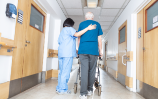 Nursing Home Fire Safety: A nurse escoring an elderly patiend down a hallway.