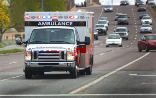 Give Employees Peace of Mind with Accident Coverage: An ambulace travelling on the highway with its lights flashing.