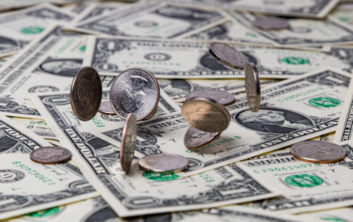 US currency laid out on a table with coins falling on top. Compensation growth slowed slightly in the third quarter of the year, signaling that the white-hot labor market is cooling off.