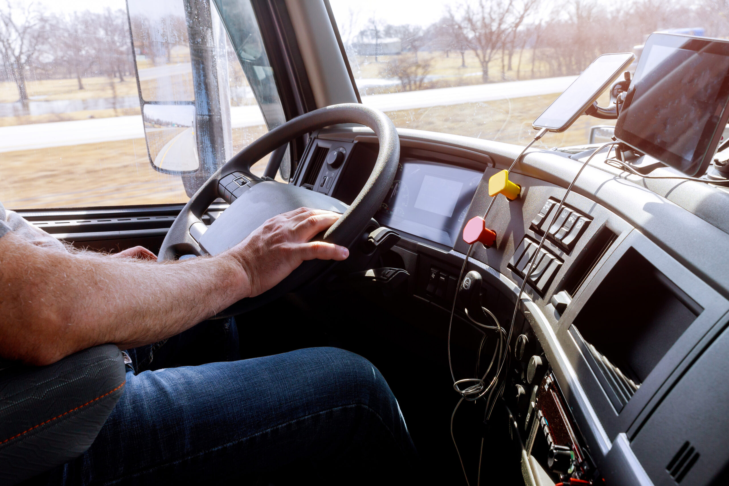 Driver in cabin of big modern truck vehicle on highway