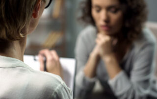 Young depressed woman talking to lady psychologist during session, mental health